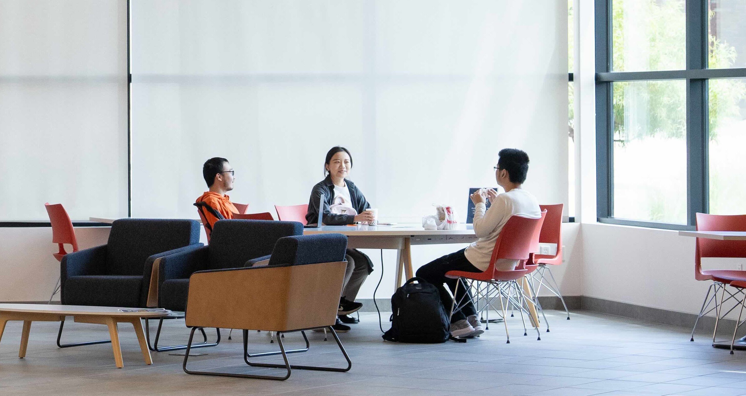 Three students are casually chatting in the lobby of the SFBU campus.