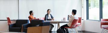 Three students are casually chatting in the lobby of the SFBU campus.