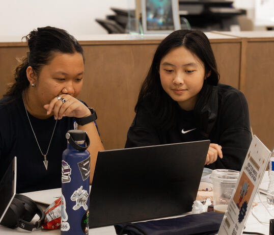 Two students were talking in front of the laptop