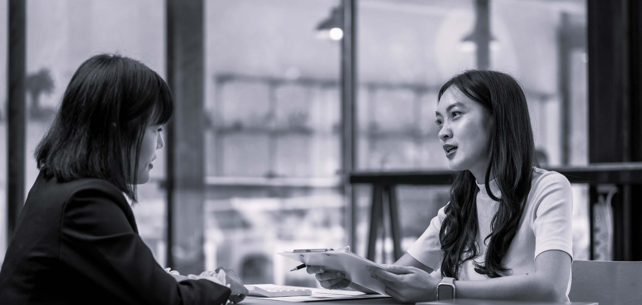 Two females having a discussion at a desk.
