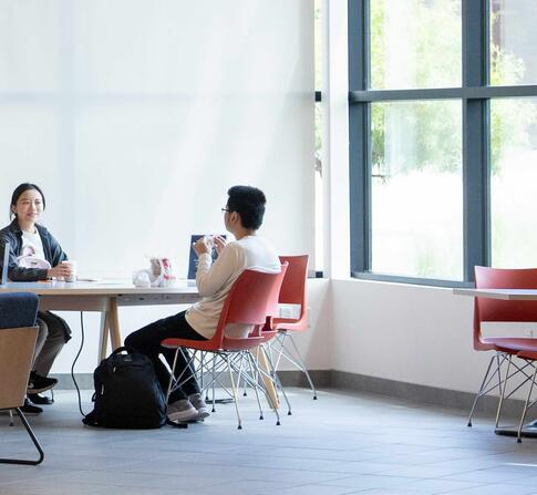 Three students are casually chatting in the lobby of the SFBU campus.