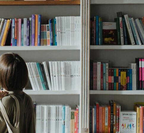 A woman browsing a bookshelf in a well-lit bookstore, exploring various titles.