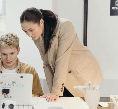Three colleagues collaborate on a laptop, embodying teamwork and creativity in a modern office environment.
