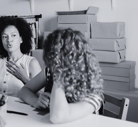 Black and white image of three females having a discussion at a table.