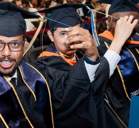 Three happy students in their cap and gowns graduating.