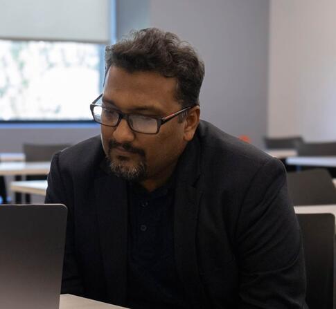 Two faculty members talking infront of a laptop.
