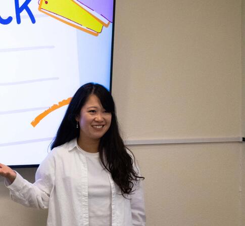 Staff member standing infront of presentation that says "good luck with finals".
