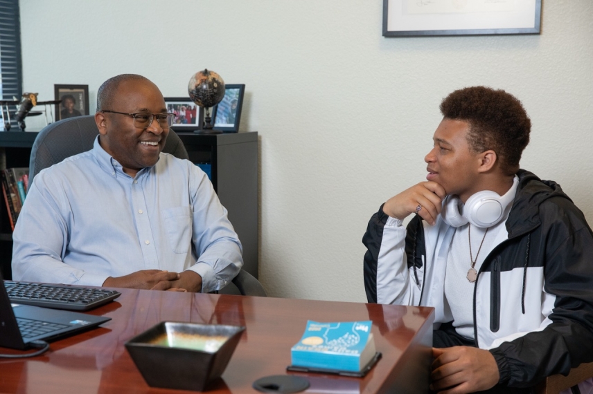 Dr. Peter Maribei is talking with a student in the Student Success Hub