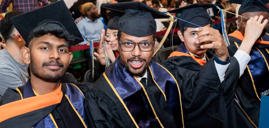 Three happy students in their cap and gowns graduating.