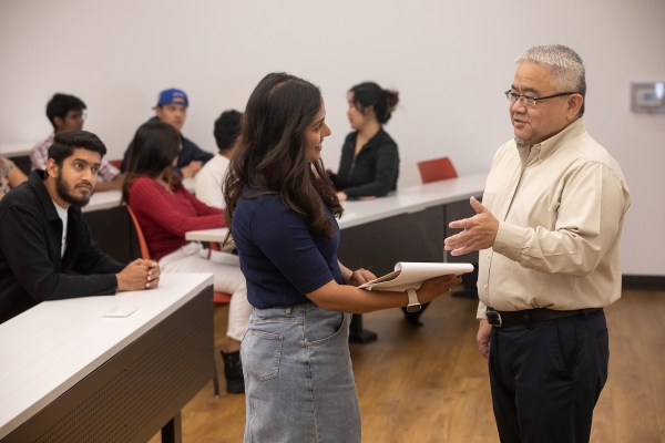 Dr.Iwagoshi is talking to a female student in the Lecture Hall with a group of students.